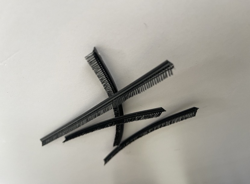 Angled-pile weatherstrip: the filament leans off the backing instead of standing square to it.